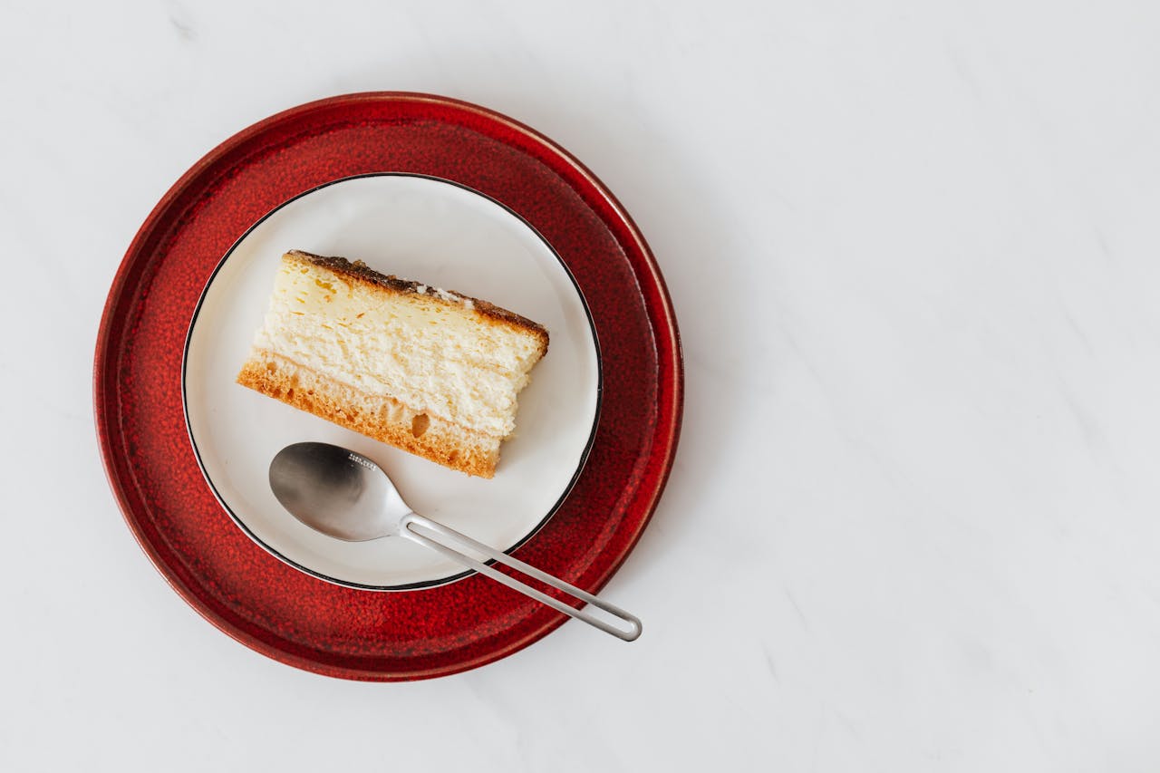 Home Top view of piece of classic cheesecake served on plate with spoon on white surface