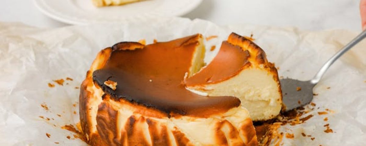 A creamy Basque burnt cheesecake with a slice served on a plate, showcasing its rich and indulgent texture.